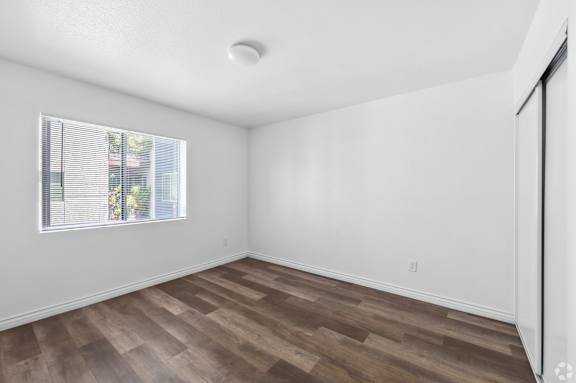 the living room of an apartment with wood flooring and a window