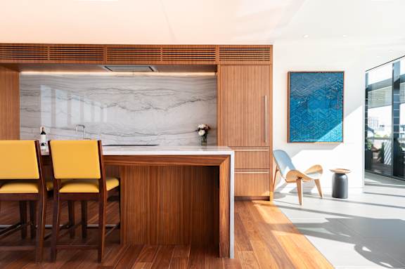 A modern kitchen with wooden cabinets and a marble backsplash.
