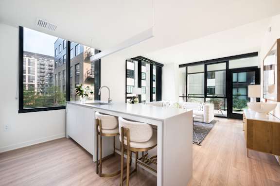 A kitchen with white countertops and wooden floors.