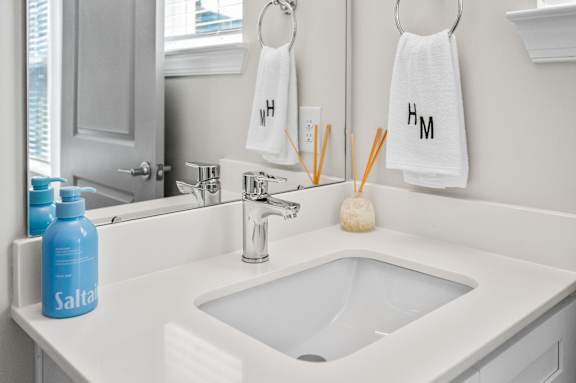 A bathroom with a white sink and a blue bottle of shampoo.