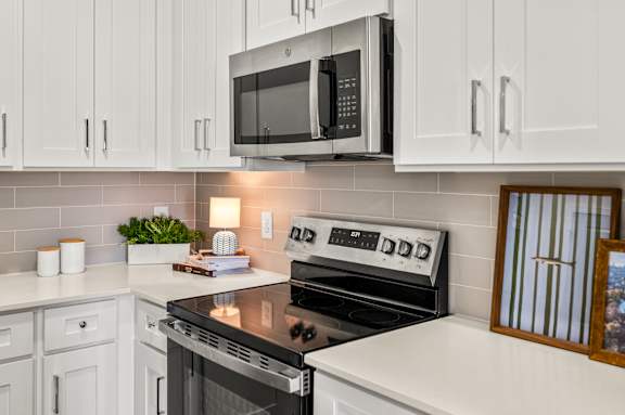 A modern kitchen with white cabinets and a black stove top.