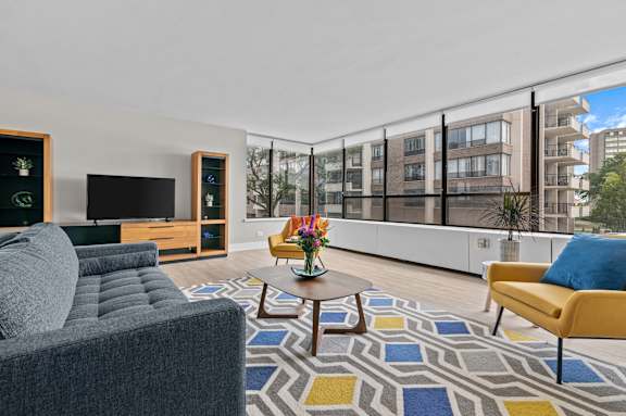 a living room with white walls and a large window with a city view