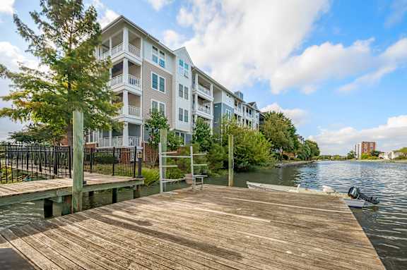 A wooden dock leads to a modern apartment building by the water.