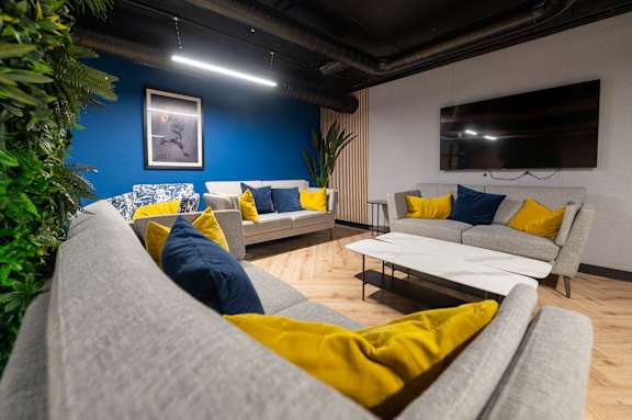 A living room with a grey couch and yellow pillows.