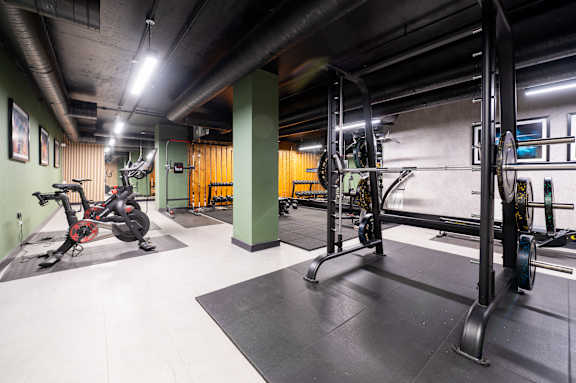 A gym with a variety of equipment including a stationary bike and a squat rack.