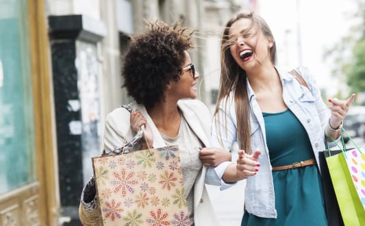 two women walking down the street with shopping bags