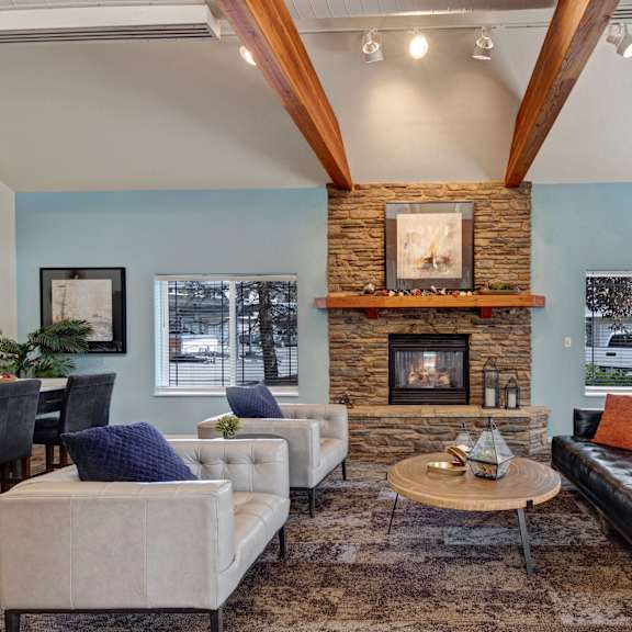 The amazing resident lounge with a fireplace, a black couch, decorations, large windows, white plush chairs, and coffee tables at the Highlands Luxury Residences. 