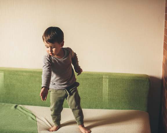 A small child is standing on a mattress at Victory Northgate Apartments, Washington, 98125