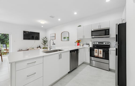 A modern kitchen with white cabinets and stainless steel appliances.