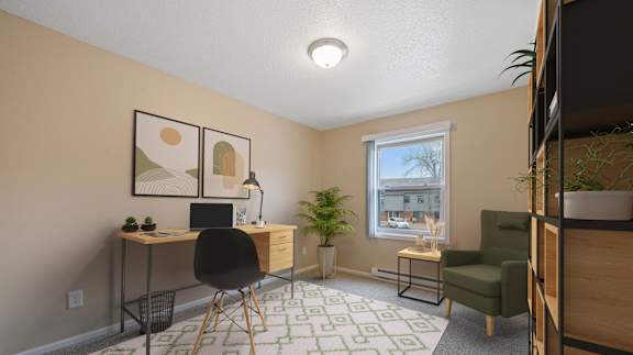 A room with a desk, chair, and potted plants.