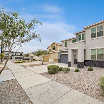 A modern house with a grey front yard and a clear blue sky.