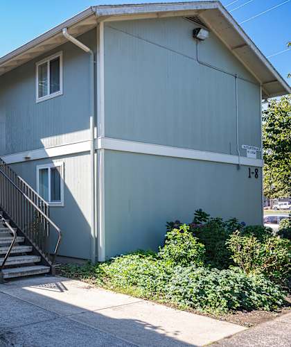 A grey house with a black metal staircase leading to the front door.