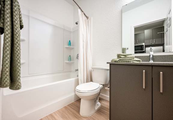 A white toilet sits in a bathroom next to a bathtub.