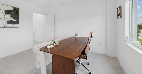 A room with a white ceiling and a brown table with a chair.