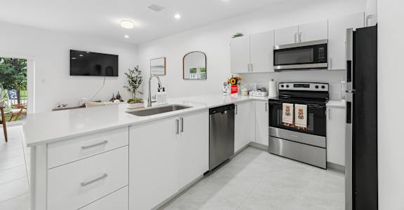 A modern kitchen with white cabinets and stainless steel appliances.