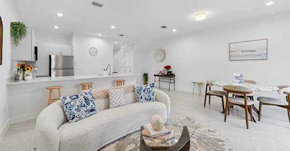 A living room with a white couch and a glass coffee table.