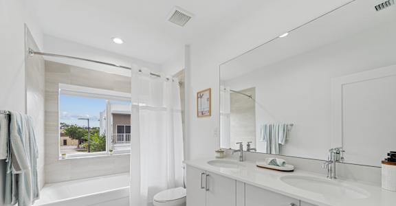 A white bathroom with a large mirror and a window.