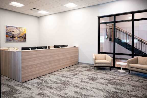 A reception area with a wooden desk and two chairs.