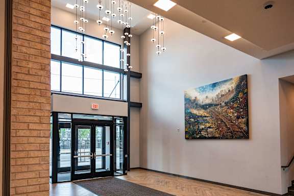 A large painting hangs on the wall in a brightly lit hallway.