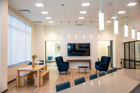 A modern office space with a long table, chairs, and a television mounted on the wall.