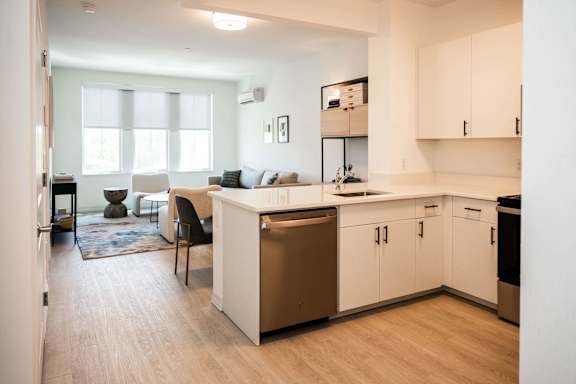 A kitchen with white cabinets and a wooden floor.