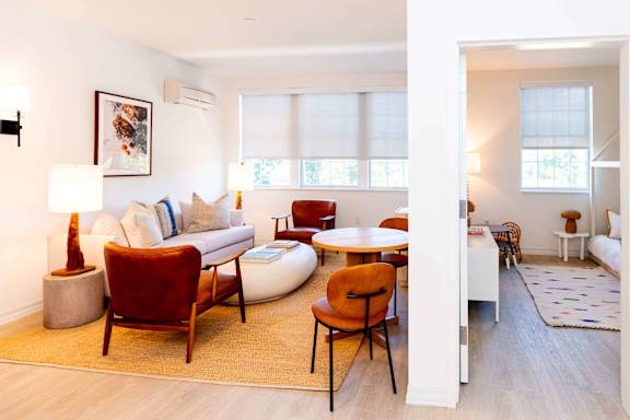 A living room with a white couch, a red chair, and a white coffee table.