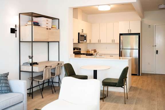 A modern kitchen with white cabinets and a dining area with white chairs and a white table.