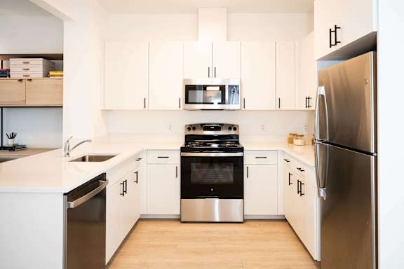 A modern kitchen with white cabinets and stainless steel appliances.