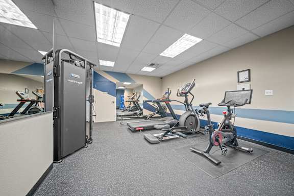 A gym with a row of exercise bikes and a treadmill.