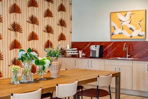 A kitchen with a wooden table and chairs, a sink, and a painting on the wall.