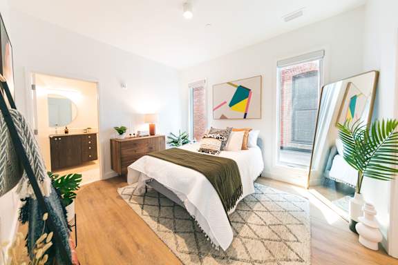 A bedroom with a bed, nightstand, and a mirror.