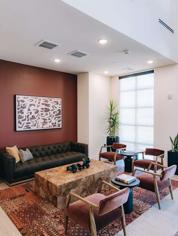 A living room with a brown sofa, a coffee table, and a large abstract painting on the wall. at Northwoods, Texas