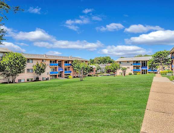 a grassy area with trees and buildings in the background