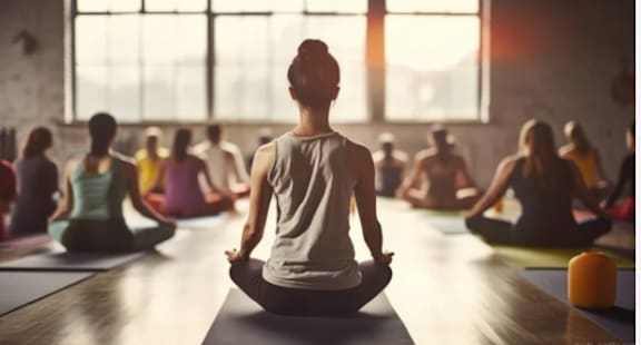 a woman sitting in a yoga class in front of a group of people