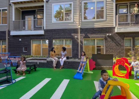 A rooftop garden with a seating area and a green lawn.