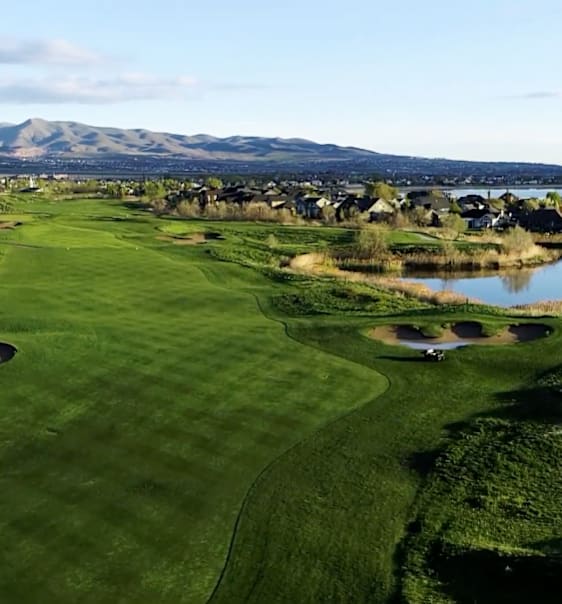 A golf course with a lake and mountains in the background.