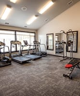 a gym with cardio equipment on the floor and a window