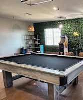 A pool table in a room with a green wallpaper.