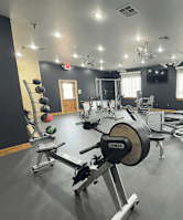 A gym with a variety of equipment including a rowing machine.