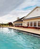 A pool in front of a building with a white exterior.