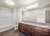 Thumbnail 25 of 26 - A bathroom with a white tub, sink, and toilet.