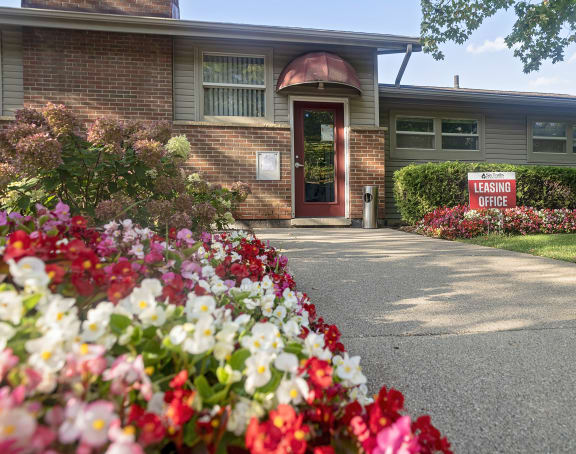 the front of a brick building with a sidewalk and flowers