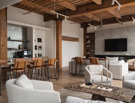 A living room with a grey couch and wooden beams on the ceiling.