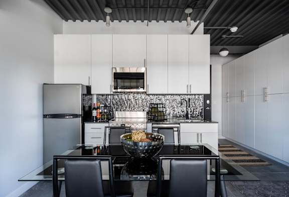 A modern kitchen with a black table and chairs.