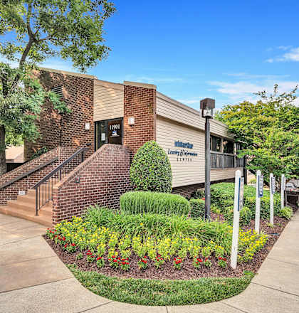 a brick building with a staircase and landscaping in front of it