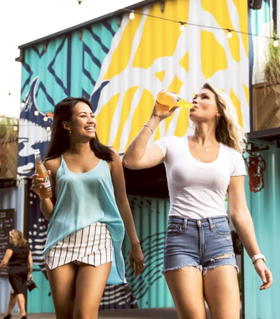 Women Walking Together Smiling and Drinking Soda