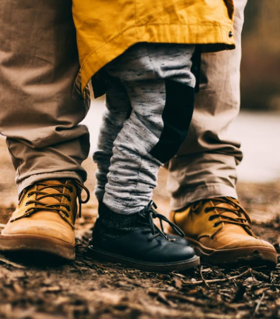 Child and Parent Wearing Boots and Standing Together on Dirt Path