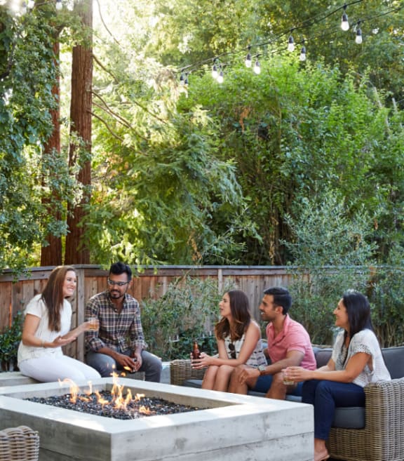 a group of people sitting around a fire pit in a backyard