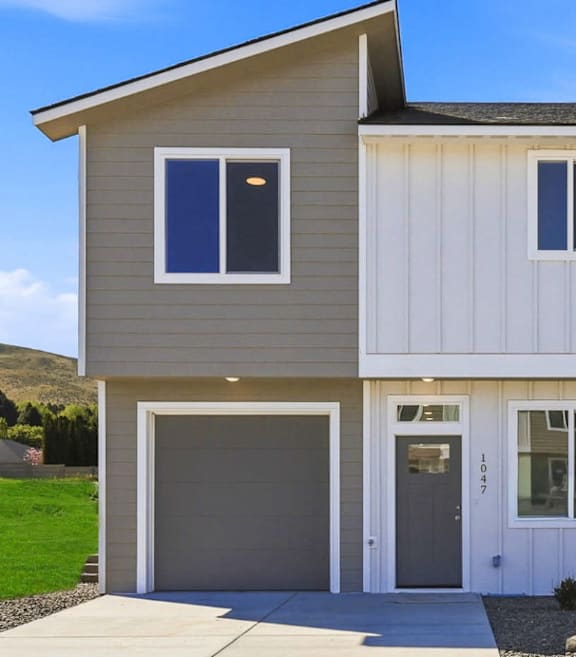 A modern house with a grey garage door and a white door.