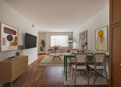 a living room with a dining room table and chairs and a flat screen tv on the wall
